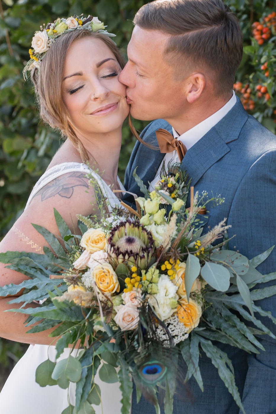Braut mit Blumenkranz und Tattoo beim zärtlichen Kuss